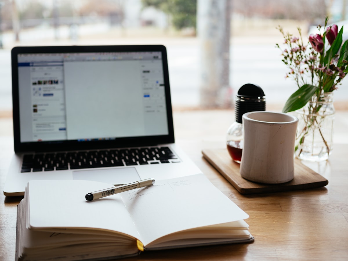 Person taking an online course on a laptop with notes and coffee